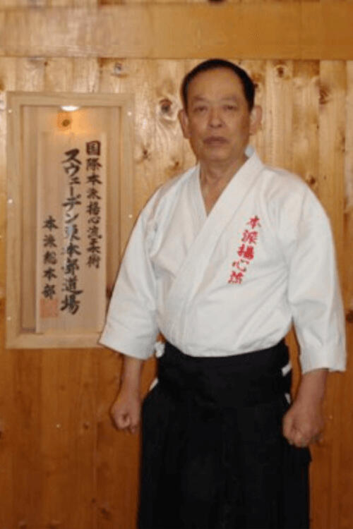 Soke Yasumoto in front of a wooden wall